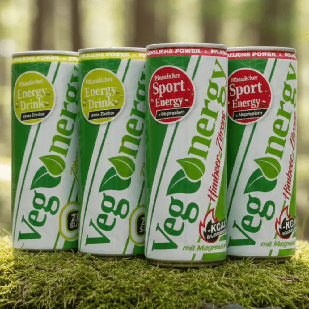 Vier Vegenergy Sport-Energy-Dosen stehen nebeneinander auf Moos im Wald, grün-weiße Dosen mit rotem Sport-Label.